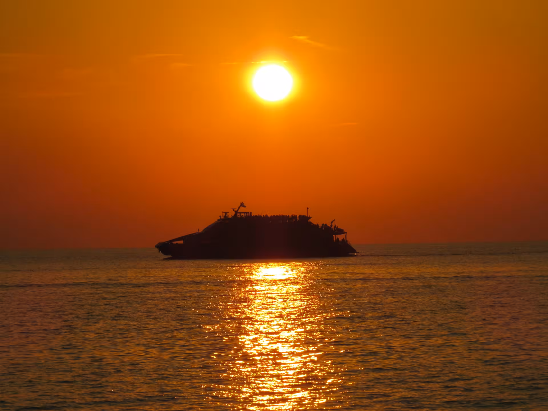 Silhouette of a boat against a stunning Tuscan sunset, perfect for a romantic Pisa and Tuscany sunset cruise.