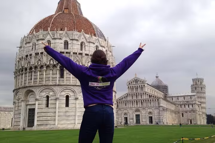 Person celebrating in front of Pisa's iconic architecture, a must-see on the Tuscany small group tour.