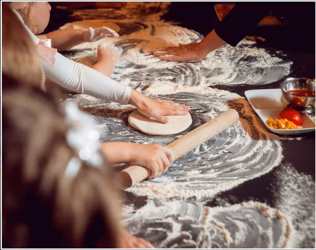 Hands of participants kneading dough in a pizza making class in Naples, surrounded by flour and fresh ingredients.