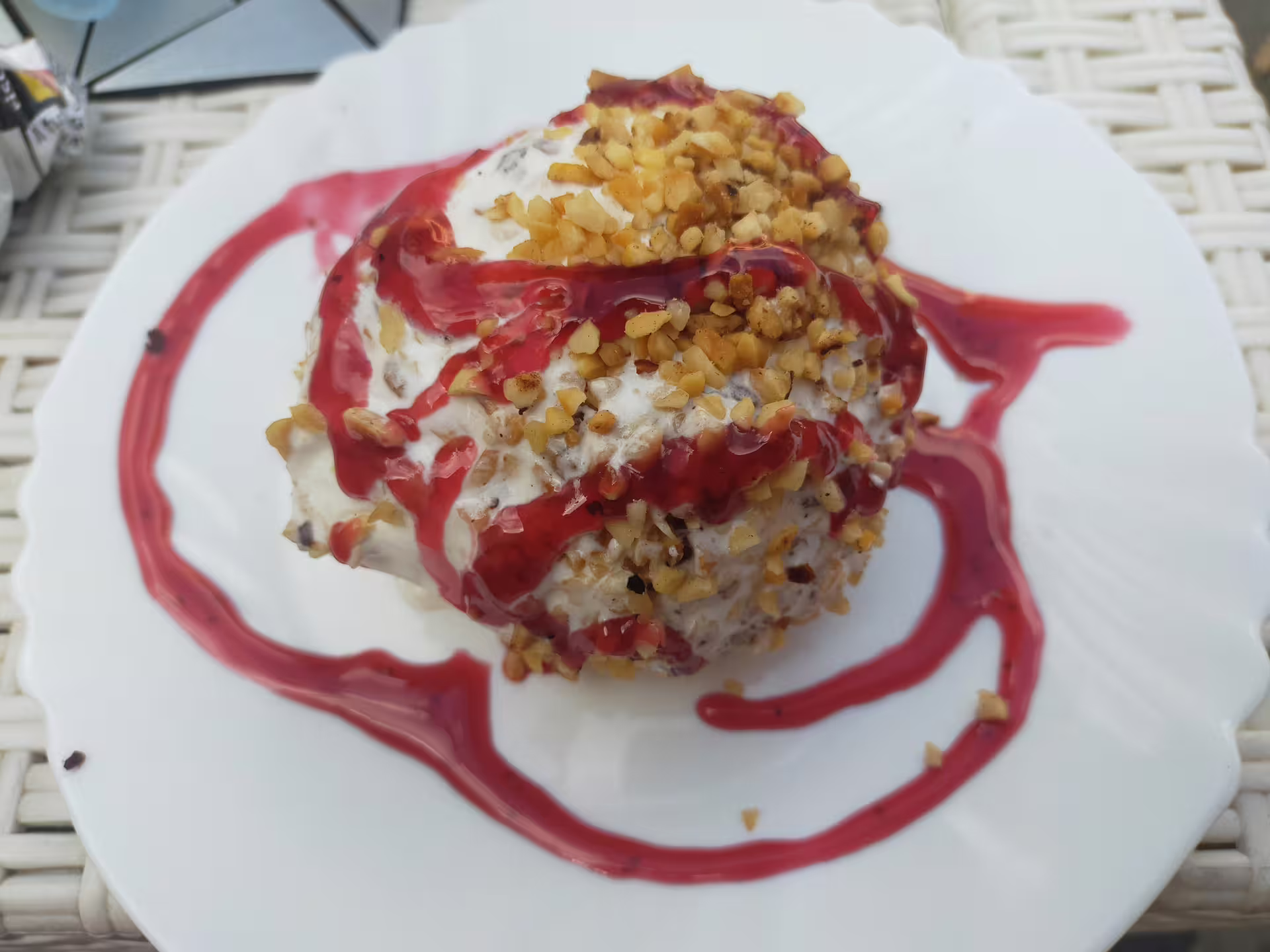 Traditional tartufo gelato dessert from Pizzo served on a white plate, topped with chopped nuts and rich red berry sauce