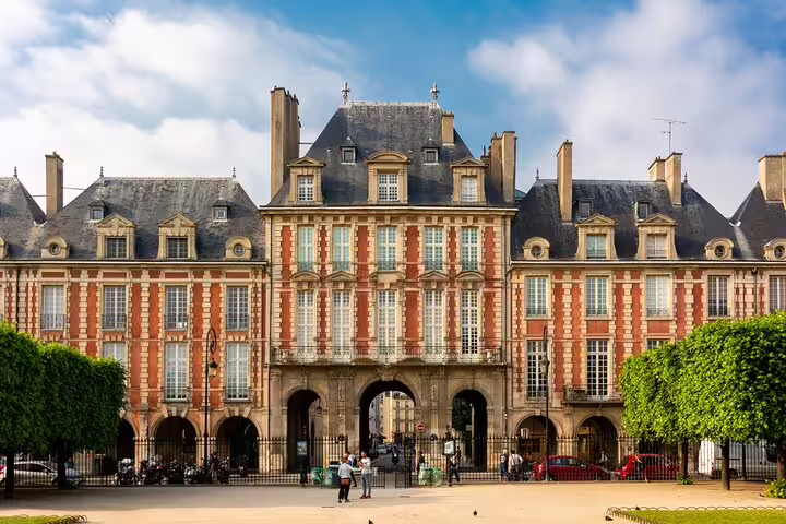 Place des Vosges historic red brick facade with arched gateway in Le Marais, Paris