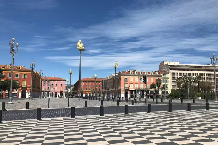 Place Masséna Nice with checkered plaza, golden sculptures on poles, and colorful baroque buildings under blue sky