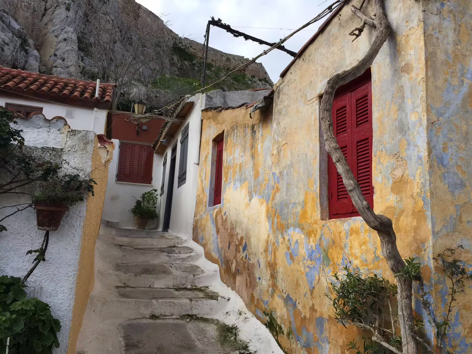 Plaka Athens alley with stone steps and red shutters, traditional houses near Acropolis walking tour