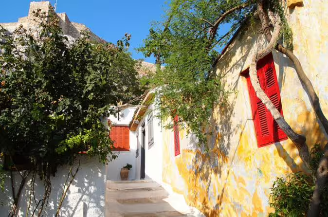 Sunny Plaka lane with whitewashed houses and red shutters near the Acropolis on Parthenon walking tour Athens