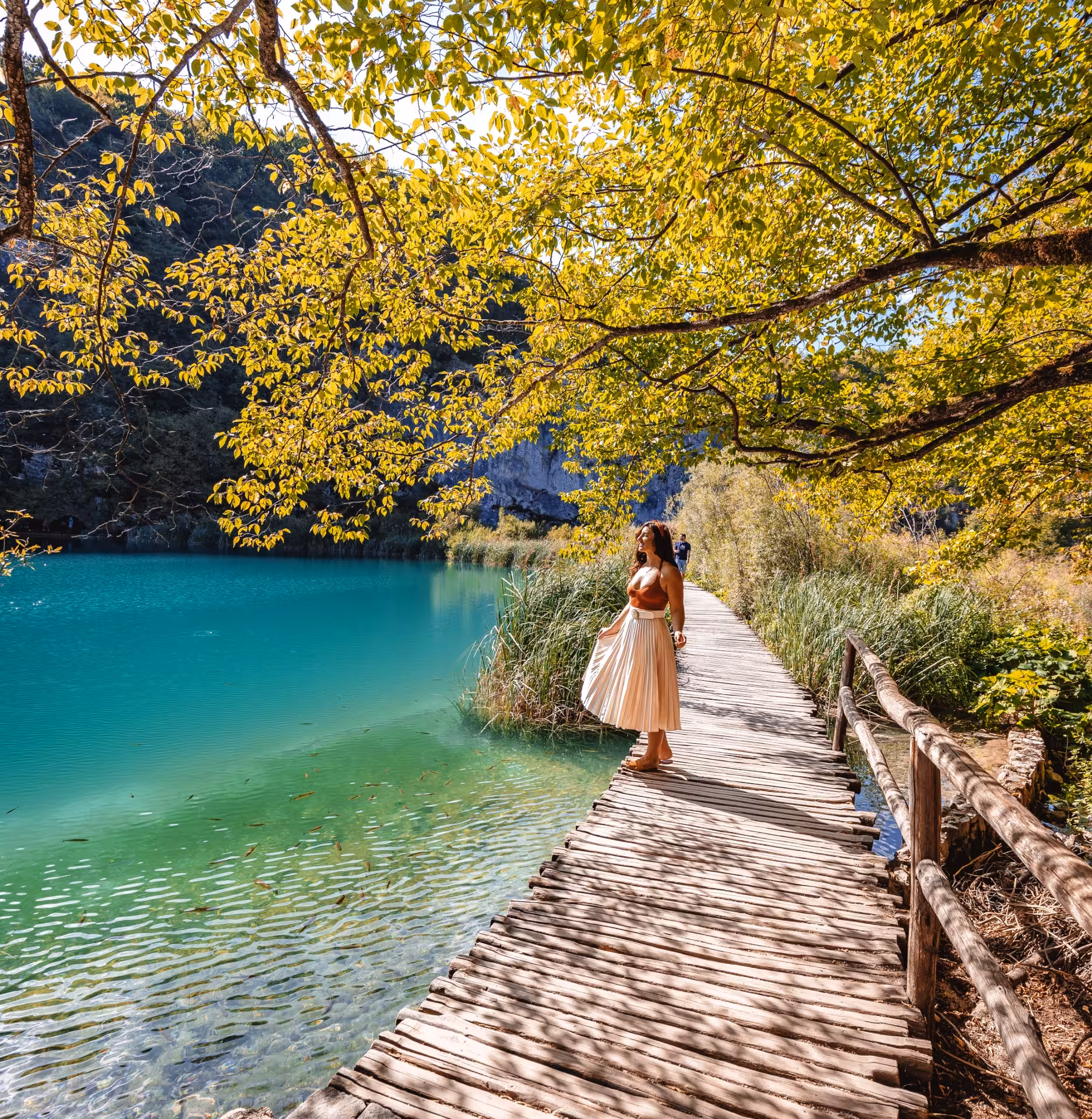 Traveler on wooden boardwalk by turquoise lake in Plitvice Lakes National Park day trip from Split