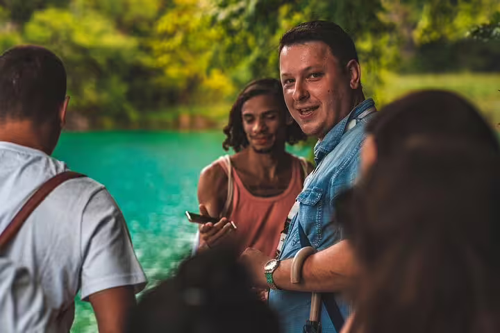 Friendly guide briefing guests by turquoise lake on scheduled Plitvice Lakes guided tour in Croatia