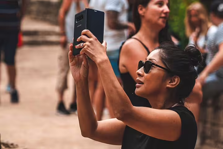 Traveler taking photos during scheduled Plitvice Lakes guided tour, capturing park scenery in Croatia