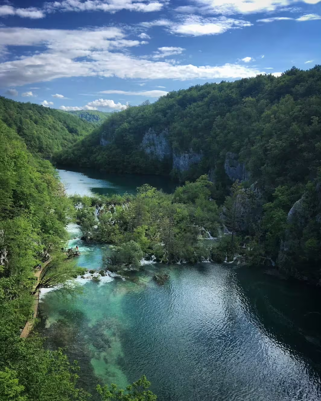 Panoramic view of Plitvice Lakes National Park on guided group tour, emerald lakes and forested cliffs
