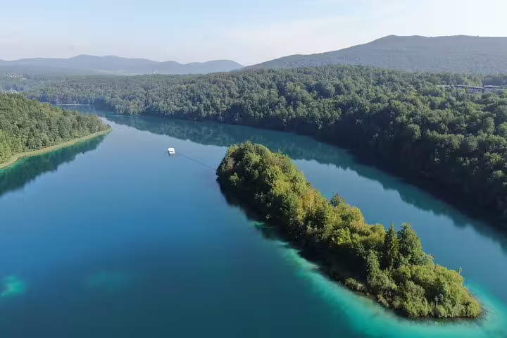 Aerial view of turquoise Plitvice Lakes with electric boat crossing, Croatia national park entry ticket