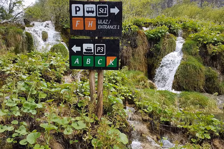Plitvice Lakes trail sign by cascading waterfalls, key stop on private tour from Zagreb to Zadar