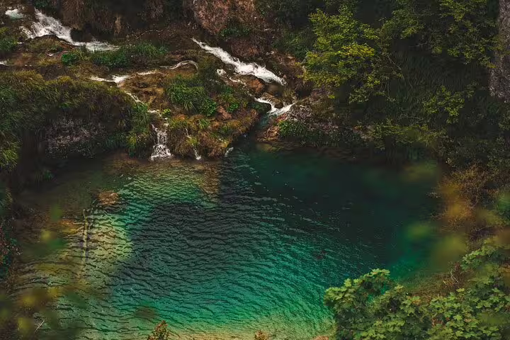 Crystal-clear turquoise lake and small waterfalls at Plitvice Lakes National Park on scheduled economy tour