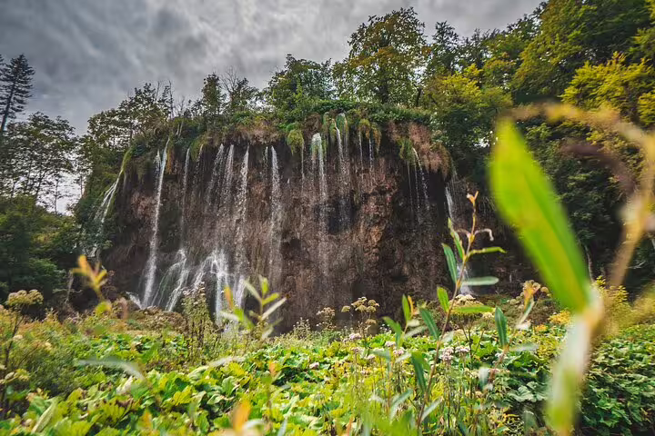 Waterfall curtain over limestone cliff at Plitvice Lakes National Park on scheduled guided tour in Croatia