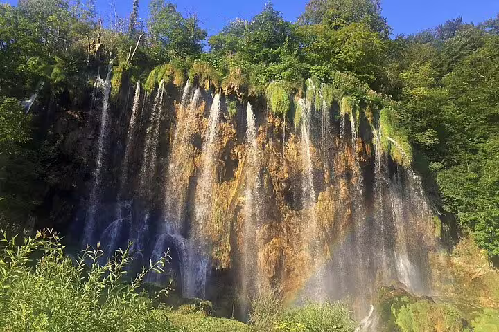 Sunlit cliffside waterfall curtain at Plitvice Lakes National Park, Croatia, on a private guided tour from Split