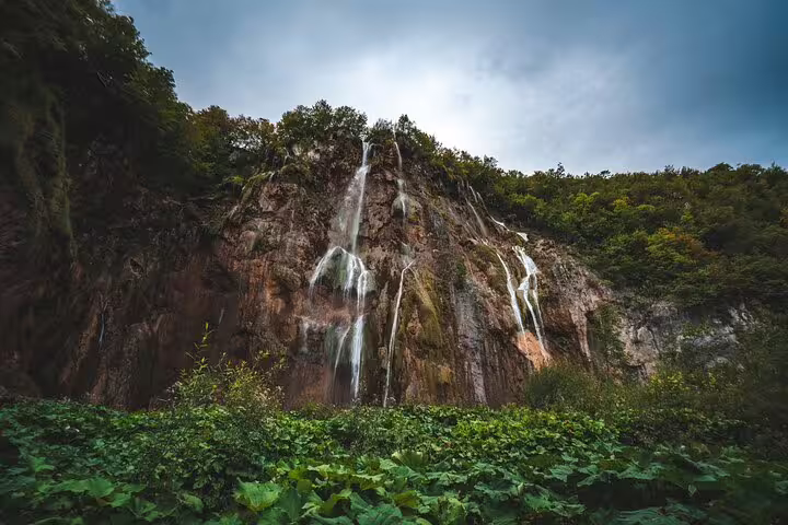 Waterfalls cascading down limestone cliffs at Plitvice Lakes National Park on a scheduled economy tour in Croatia