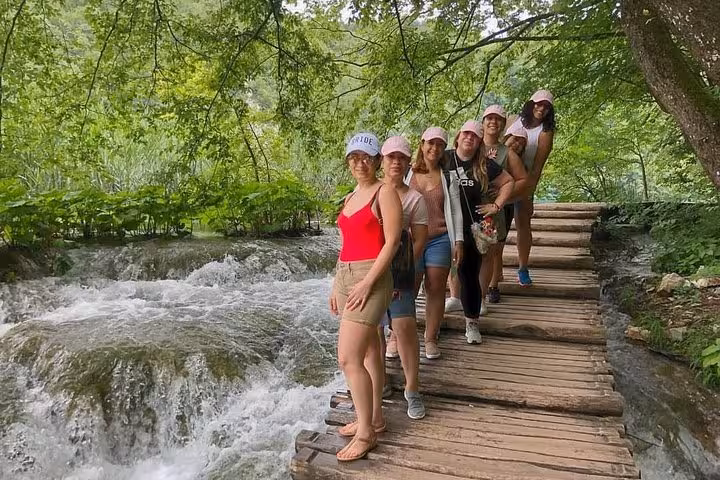 Small group walking Plitvice Lakes wooden trail beside rapids on Zagreb to Split private tour via Rastoke