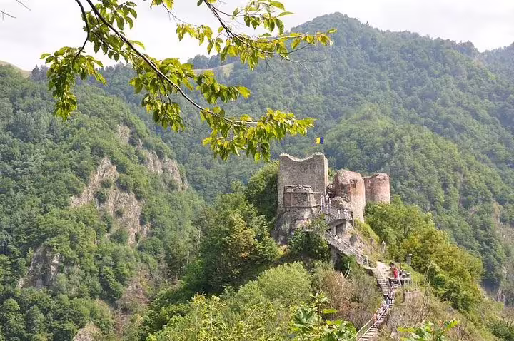 Ruins of Poienari Fortress perched on a rocky cliff surrounded by green forested mountains in Romania