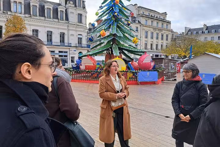 Group listens to guide near festive decorations in Poitiers, exploring cultural heritage during a walking tour.