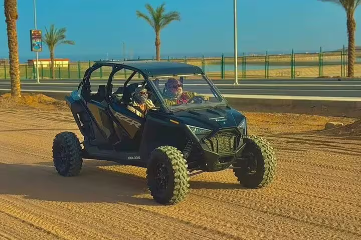 Couple riding Polaris RZR buggy near Sharm El Sheikh on double buggy desert safari adventure with sea views