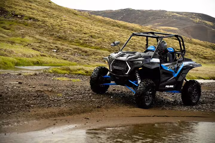 Polaris RZR buggy splashing through muddy terrain on Golden Circle tour in Iceland