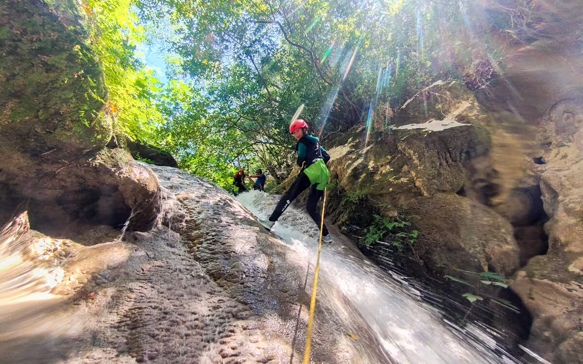 Rappelling down a waterfall chute on Polylimnio canyoning tour in Messinia, Greece, guided adventure