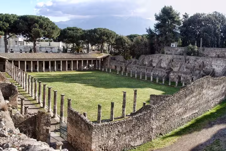 Visit the historic amphitheater of Pompeii with lush greenery, included in the skip-the-line Sorrento tour package.