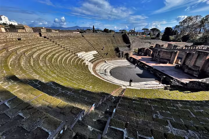 View of the ancient amphitheater in Pompeii under a blue sky, featured in a guided tour from Positano.