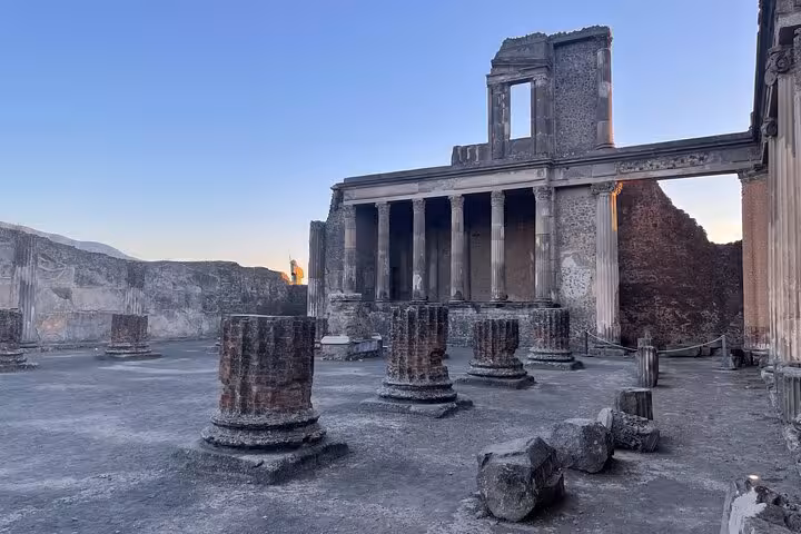 Ruins of Pompeii's ancient forum with crumbling columns under a clear sky, part of the semi-private tour from Positano.