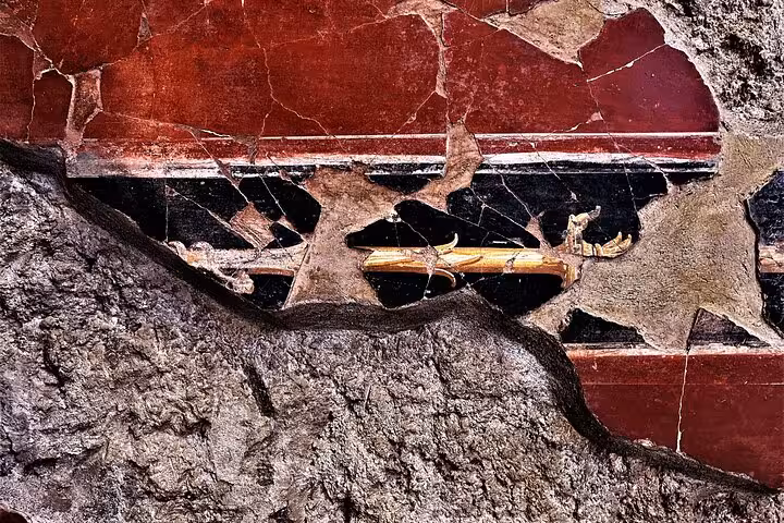 Close-up of ancient fresco detail in Pompeii, showcasing vibrant red and black colors on a guided tour with skip-the-line entry.