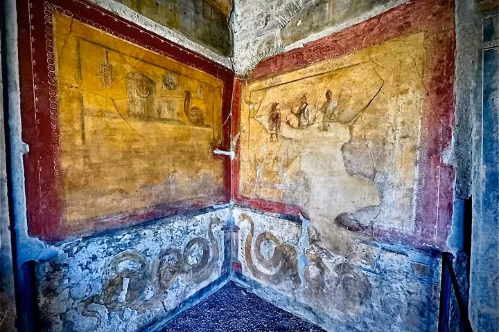 Ancient frescoes in a preserved room at Pompeii, showcasing vibrant historical art on a private tour with skip-the-line access.