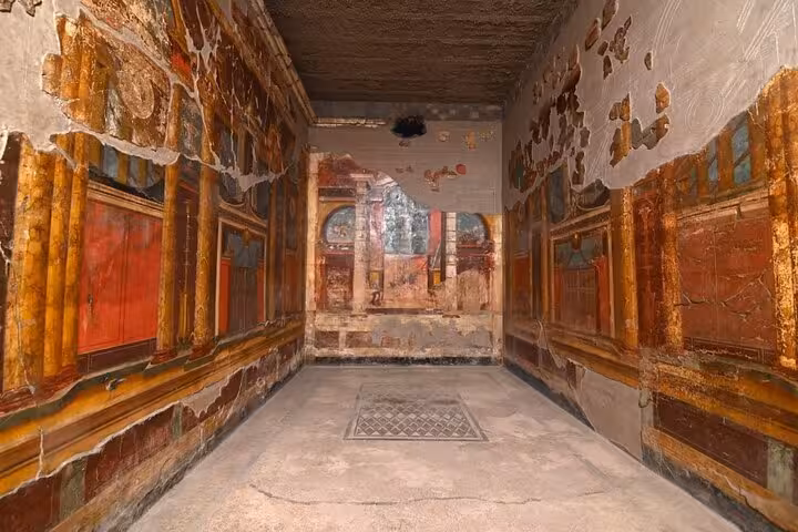 Vibrant frescoes adorn the ancient walls of a room in Pompeii, showcasing Roman artistry on a private walking tour.