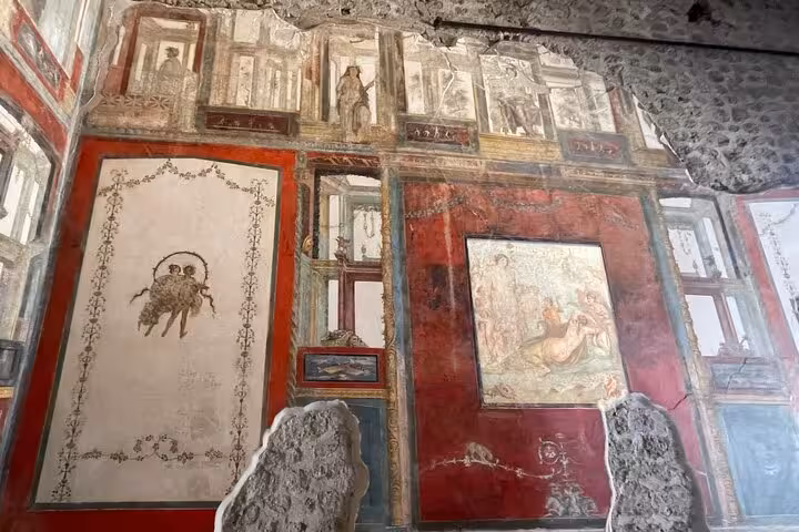 Intricate ancient frescoes on a wall in Pompeii, illustrating the rich history explored on the Sorrento tour.