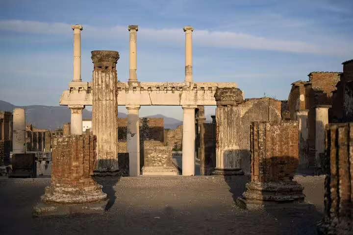 Ancient Roman columns and ruins at the Pompeii archaeological site with mountains in background