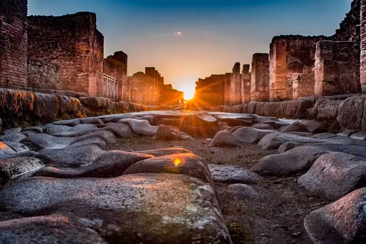Ancient Roman street in Pompeii ruins at sunset with worn stone pavement and crumbling brick walls