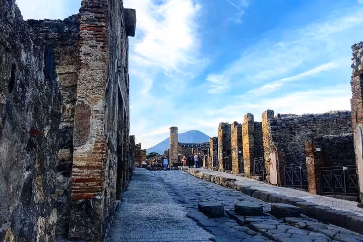 Historic cobblestone street lined with ancient ruins in the archaeological site of Pompeii.