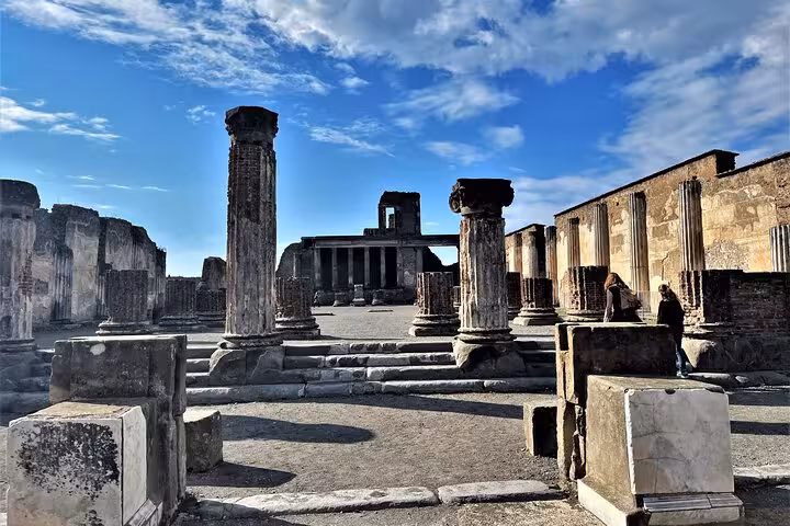 Explore ancient ruins with towering columns under a clear sky on the semi-private Pompeii tour from Positano.