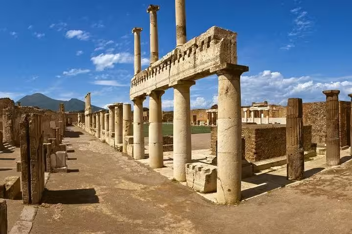 Explore the ancient ruins of Pompeii with its iconic columns and Mount Vesuvius in the background on our full-day tour.