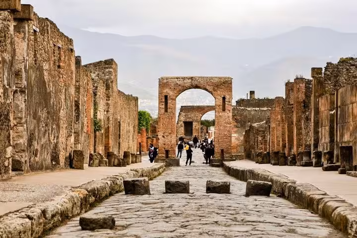 Ancient streets of Pompeii with well-preserved ruins and arches, offering a glimpse into Roman history and architecture.