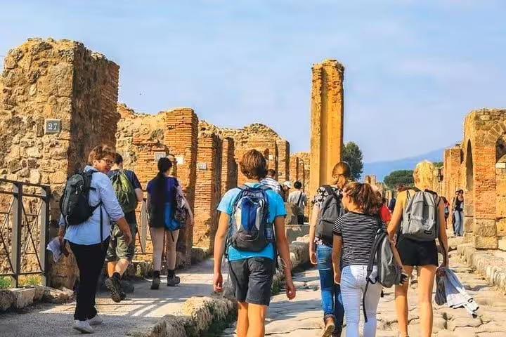 Tourists explore ancient Pompeii ruins on a sunny day during the Pompeii Experience from Sorrento tour.