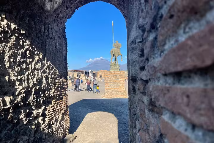Archway view of Pompeii ruins with Mount Vesuvius in the background on a guided tour from Naples.