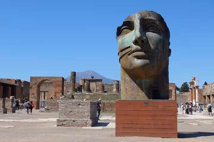 Explore ancient Pompeii with a stunning bronze sculpture and Mount Vesuvius backdrop on a private guided tour from Positano.