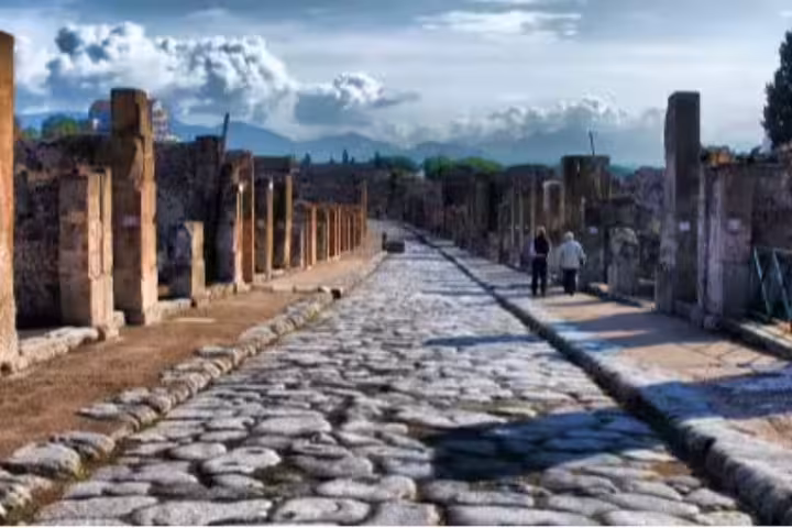 Cobblestone street in Pompeii archaeological park on guided group walking tour through ancient excavations