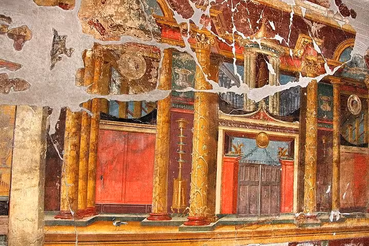 Vibrant fresco with detailed architecture in the ruins of Pompeii, showcasing ancient Roman artistry and culture.