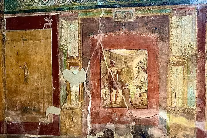 Faded fresco depicting a mythological scene in Pompeii, showcasing ancient Roman art on a guided tour from Naples.
