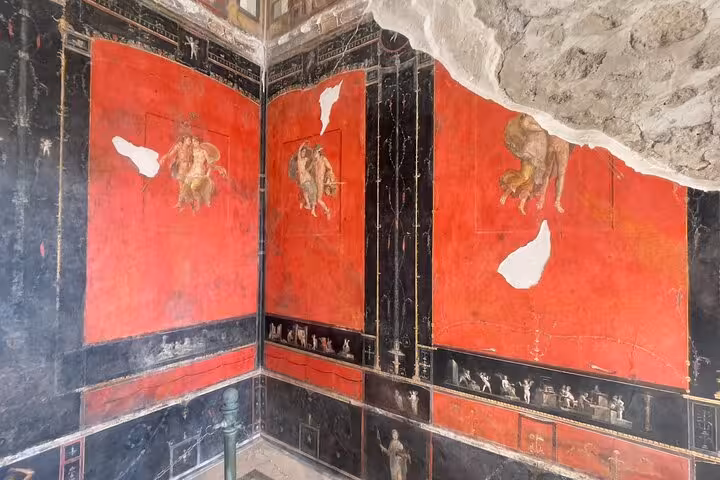 Intricate frescoes with vibrant red backgrounds in the ancient ruins of Pompeii, showcasing Roman artistry.