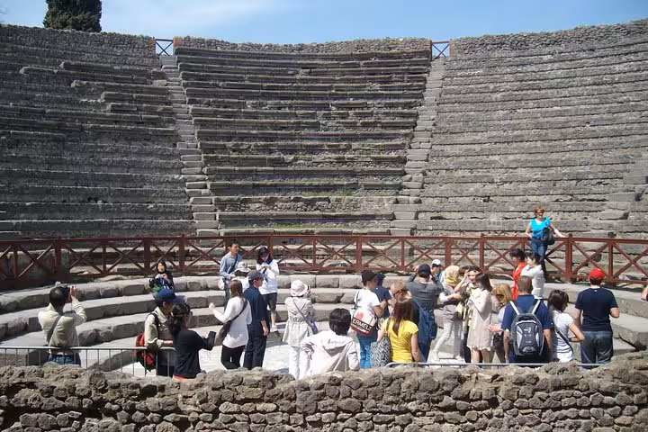 Tourists exploring Pompeii's amphitheater during a guided tour with lunch from Sorrento, showcasing historic allure.