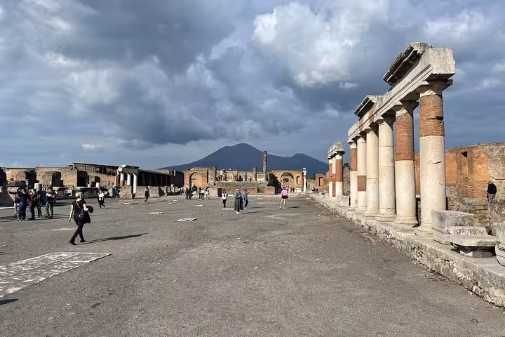 Visitors explore the ancient ruins of Pompeii with Mount Vesuvius in the background, highlighting the site's historical significance.