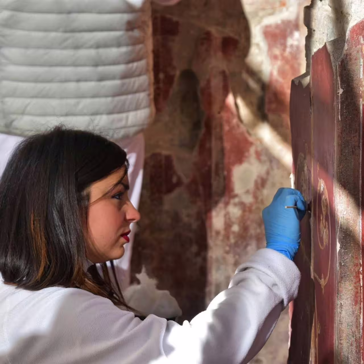 Restorer working on Pompeii fresco, highlight of Pompeii & Herculaneum group tour from Naples with guide