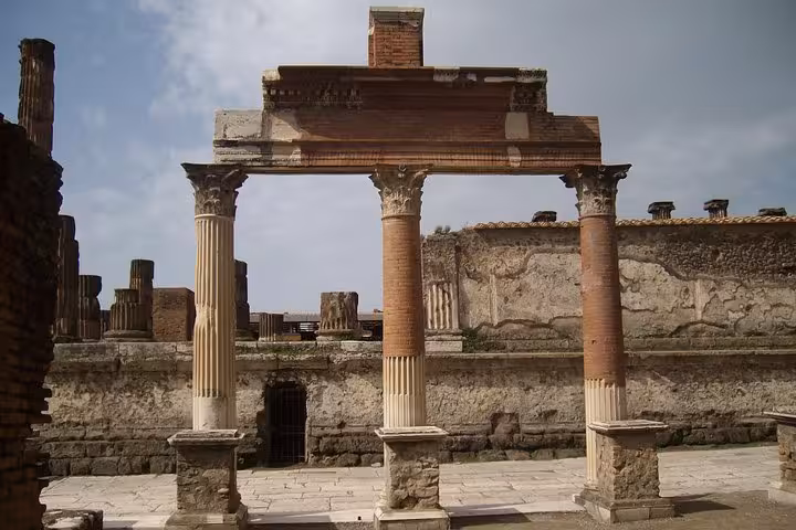 Explore ancient ruins of Pompeii with well-preserved columns and architecture on a guided tour including Herculaneum.