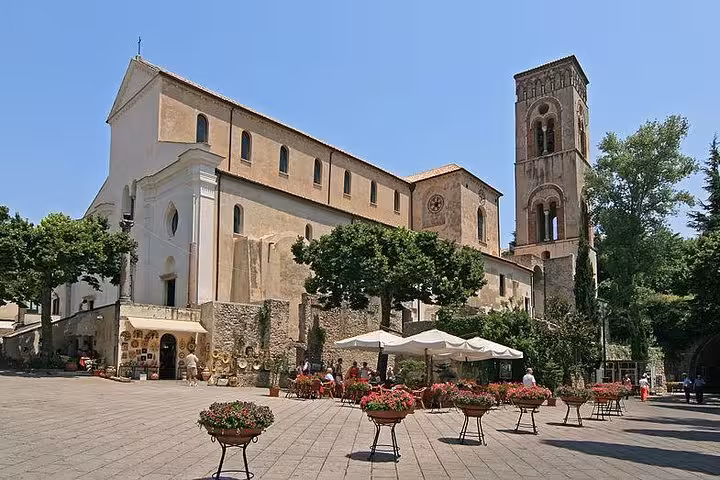 Historic church and bell tower in a sunny square adorned with flower pots in Pompeii, Italy.