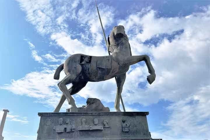 Statue of a rearing horse and rider against a blue sky at the Pompeii archaeological site, perfect for Amalfi Coast tours.